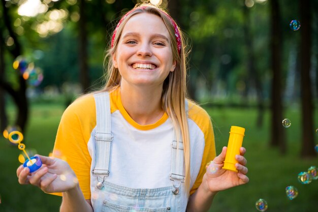 Mujer feliz jugando con burbujas al aire libre