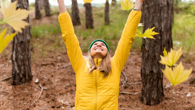 Mujer feliz jugando con hojas de otoño