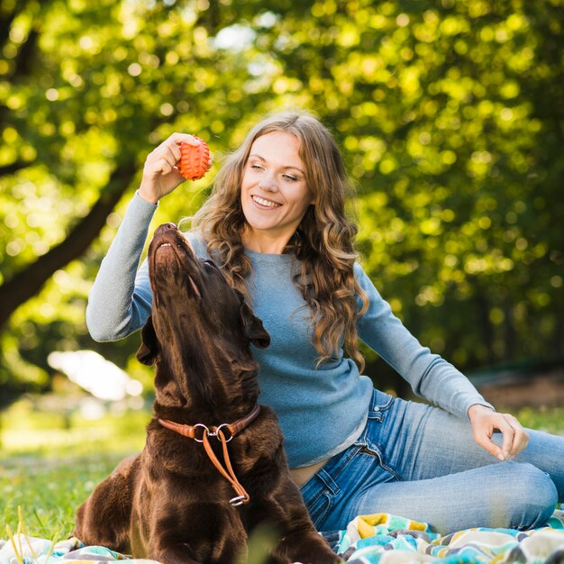 Mujer feliz jugando con su perro en el jardín