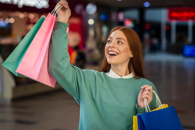 Mujer feliz levantando bolsas de compras