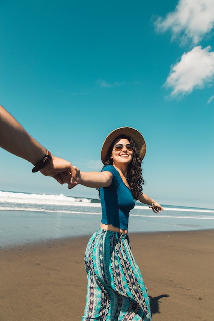 Mujer feliz líder hombre a través de la arena de la playa