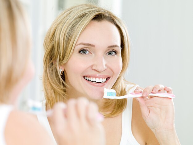mujer feliz, limpieza de dientes, con, cepillo de dientes