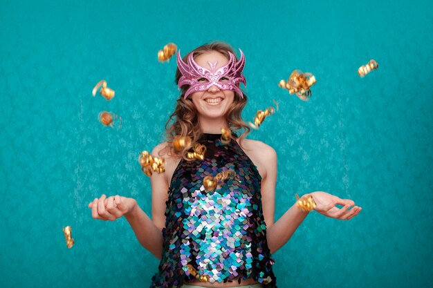 Mujer feliz con máscara rosa y confeti dorado