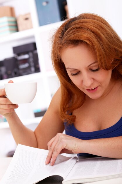 Mujer feliz de mediana edad con diario y taza