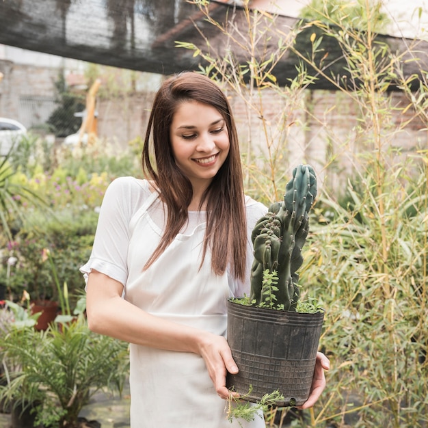 Mujer feliz mirando cactus en invernadero