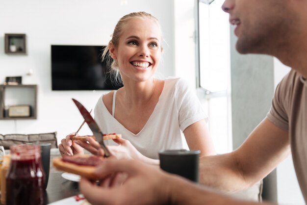 Mujer feliz mirando a su hombre mientras desayunan