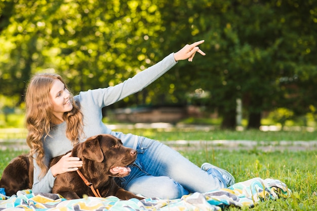 Foto gratuita mujer feliz mostrando algo a su perro en el jardín