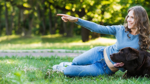 Mujer feliz mostrando algo a su perro en el parque