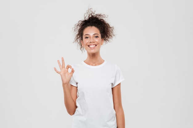 Mujer feliz mostrando signo bien y mirando a la cámara