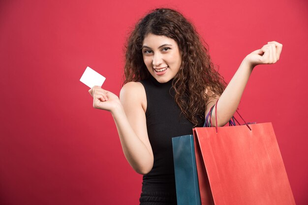 Mujer feliz con muchas bolsas y tarjetas bancarias en rojo