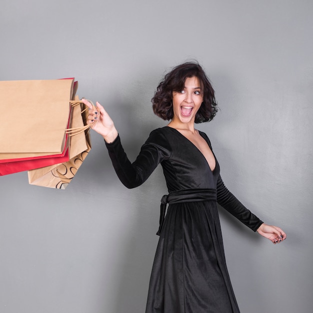 Mujer feliz en negro con bolsas de compras