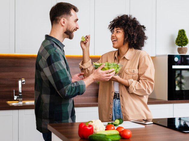 Mujer feliz ofreciendo ensalada a su novio