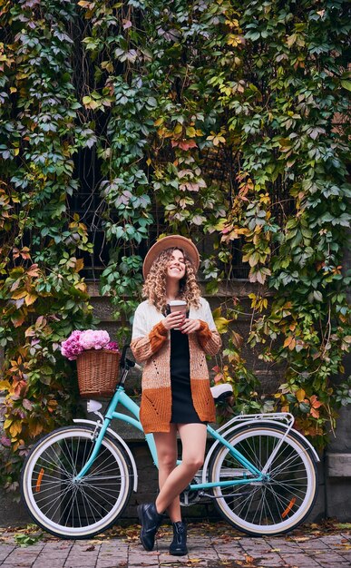 Mujer feliz parada cerca de una bicicleta antigua en el parque de la ciudad