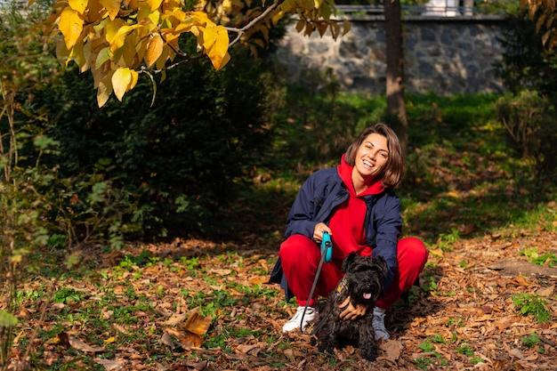 Mujer feliz en el parque con hojas otoñales