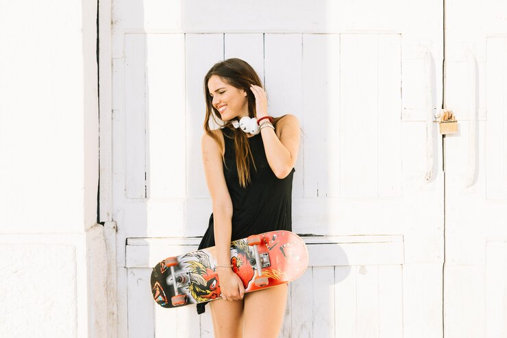 Foto gratuito mujer feliz con patineta de pie delante de la puerta