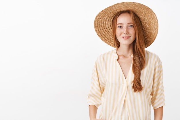 Mujer feliz con pelo rojo y pecas en el moderno sombrero de paja y blusa amarilla sonriendo tierna y femenina tomando fotos de la vieja Europa