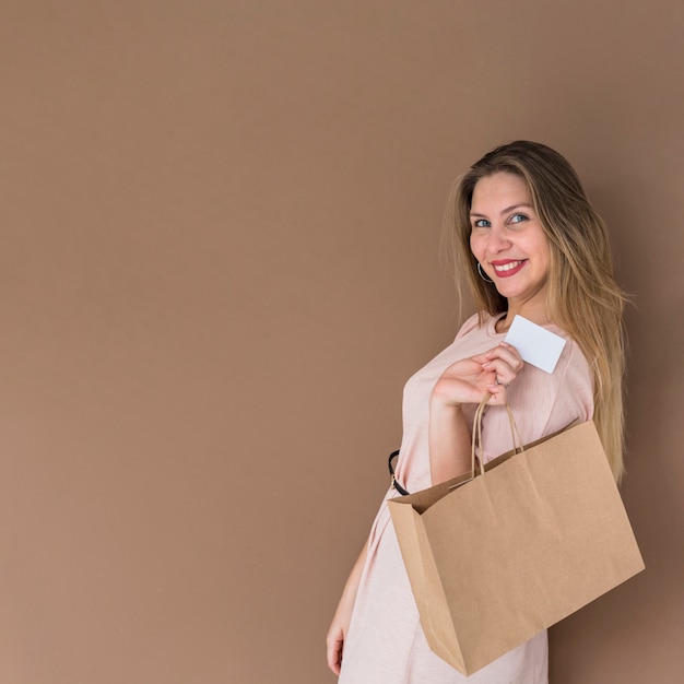 Mujer feliz de pie con bolsa y tarjeta de crédito