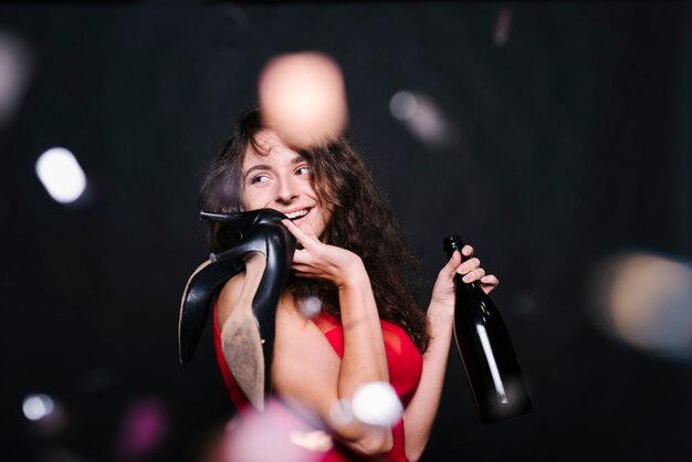 Mujer feliz de pie con la botella en la fiesta