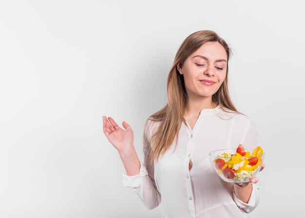 Mujer feliz de pie con ensalada de verduras en un tazón