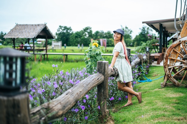 Mujer feliz de pie en el jardín de flores en las barandillas de madera
