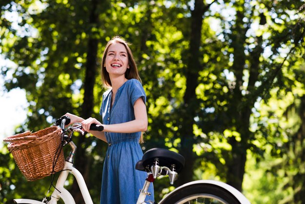 Mujer feliz de pie junto a la bicicleta