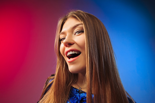 La mujer feliz de pie y sonriendo contra el espacio de color.