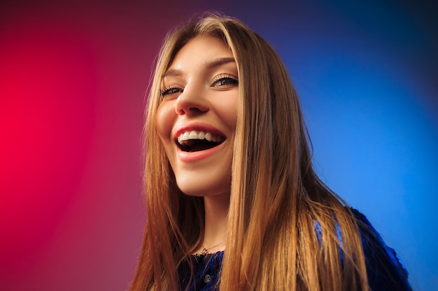 La mujer feliz de pie y sonriendo contra el espacio de color.