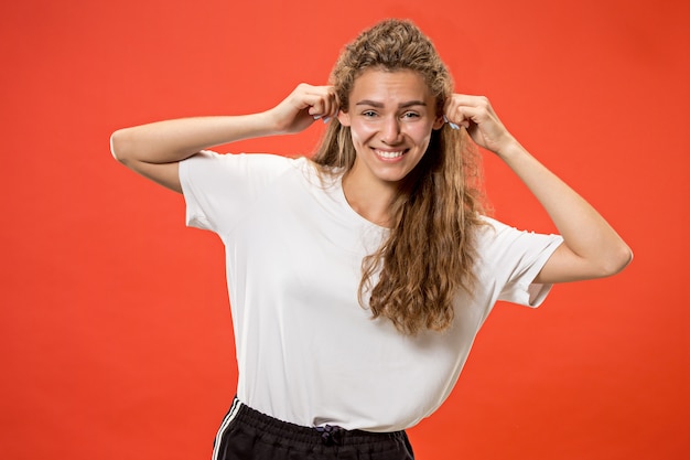 mujer feliz de pie y sonriendo contra rojo