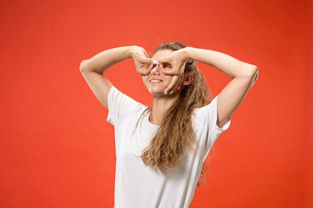 Foto gratuita mujer feliz de pie y sonriendo contra rojo