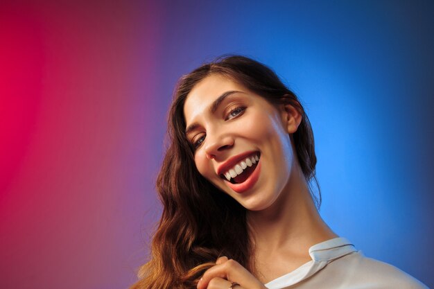 Mujer feliz de pie y sonriendo en la pared de color