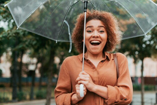 Mujer feliz de pie bajo su paraguas en otoño