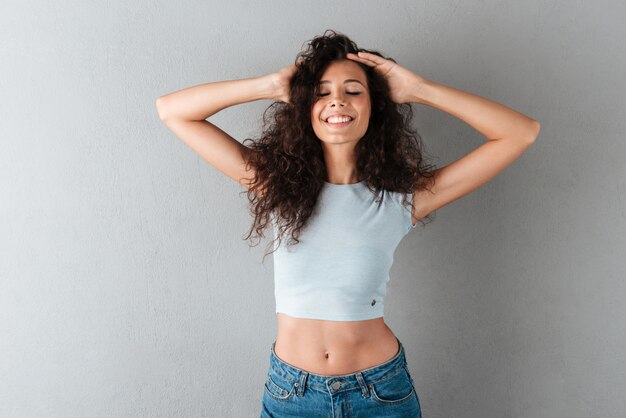 Mujer feliz posando aislada sobre gris