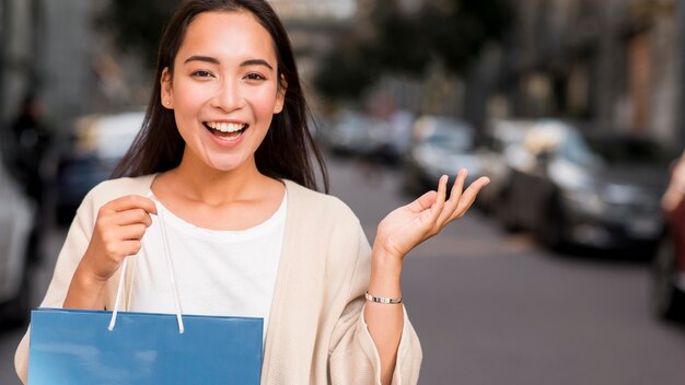 Mujer feliz posando al aire libre con bolsa de compras y espacio de copia