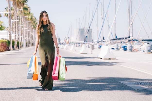 Mujer feliz posando con las bolsas de las compras en un día soleado