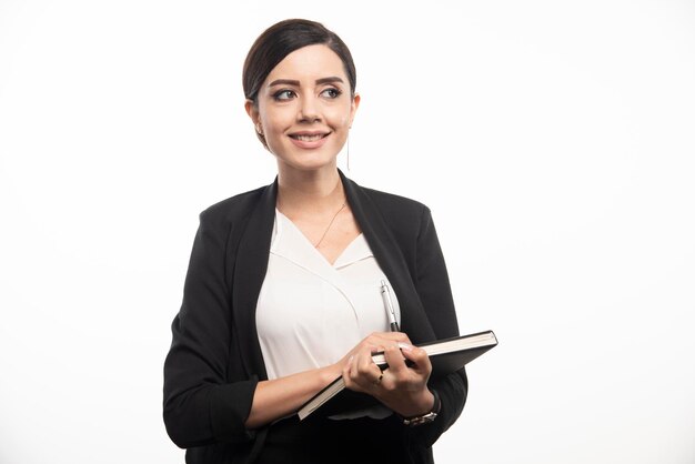 Mujer feliz posando con cuaderno sobre fondo blanco. Foto de alta calidad