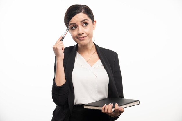 Mujer feliz posando con cuaderno sobre fondo blanco. Foto de alta calidad