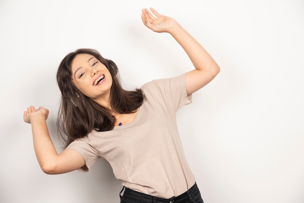 Mujer feliz posando con la mano hacia arriba sobre fondo blanco.