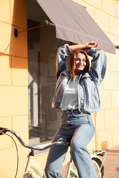 Foto gratuita mujer feliz posando en su bicicleta en la calle