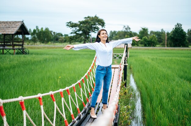 mujer feliz en un puente de madera en un prado verde en un día soleado