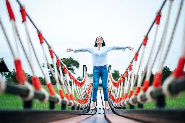 mujer feliz en un puente de madera en un prado verde en un día soleado