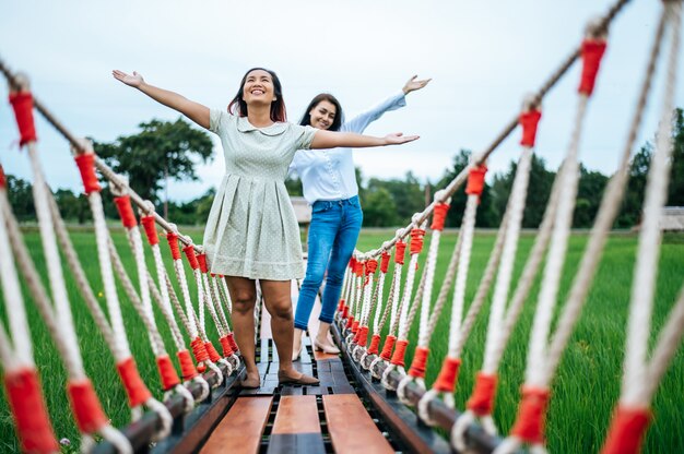 mujer feliz en un puente de madera en un prado verde en un día soleado