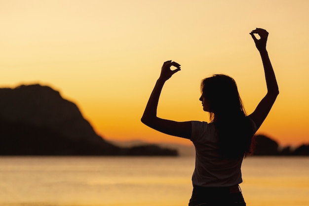 Mujer feliz y puesta de sol en el fondo