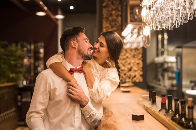 Mujer feliz que abraza al hombre alegre en el contador de la barra