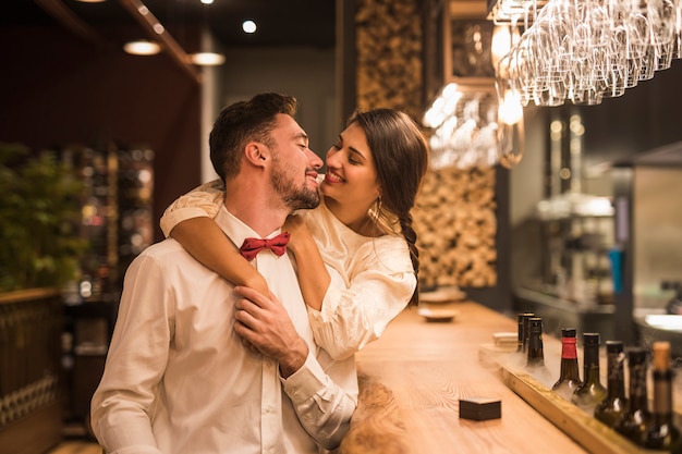 Mujer feliz que abraza al hombre alegre en el contador de la barra