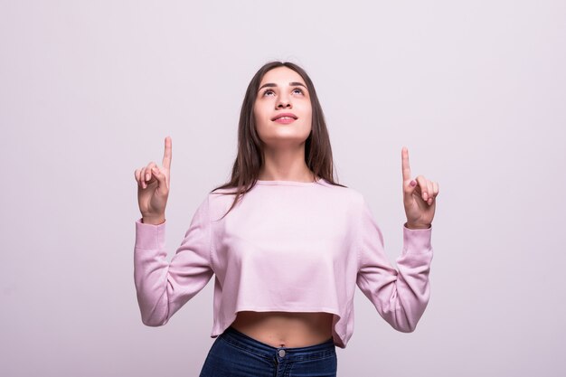 Mujer feliz que destaca con su dedo aislado sobre blanco