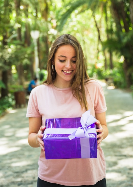 Foto gratuita mujer feliz que mira la caja de regalo púrpura