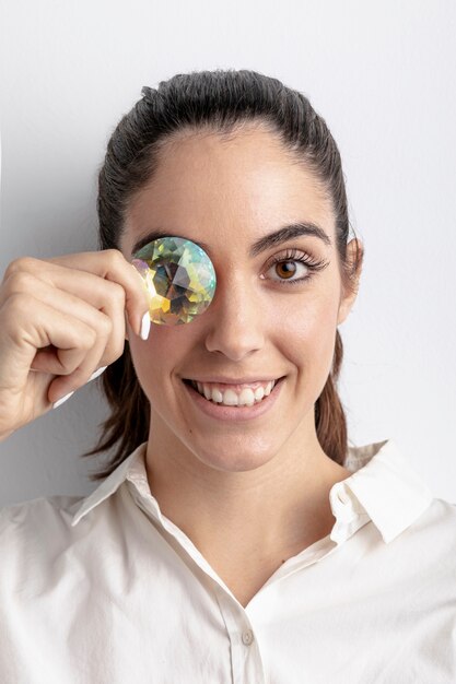 Mujer feliz que presenta con el diamante que cubre el ojo