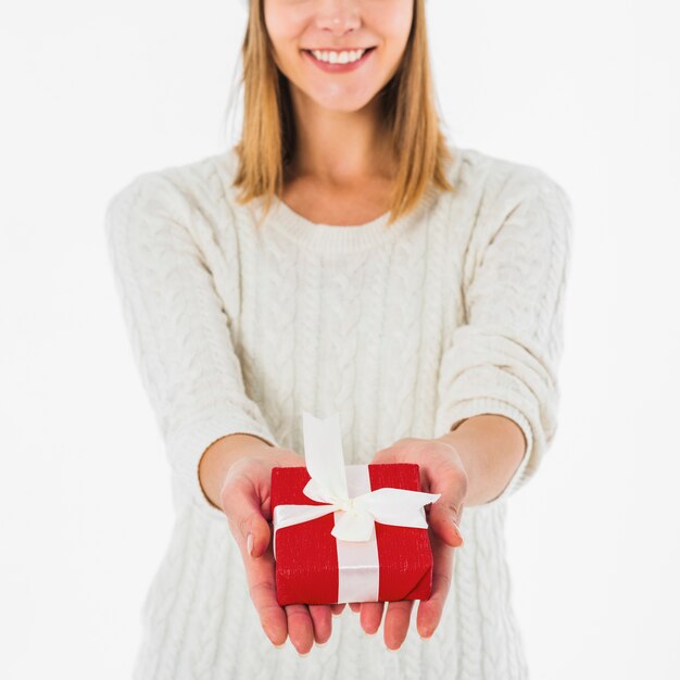 Mujer feliz que sostiene la caja de regalo roja en manos
