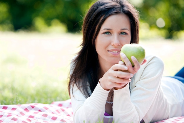 Mujer feliz que sostiene la manzana verde