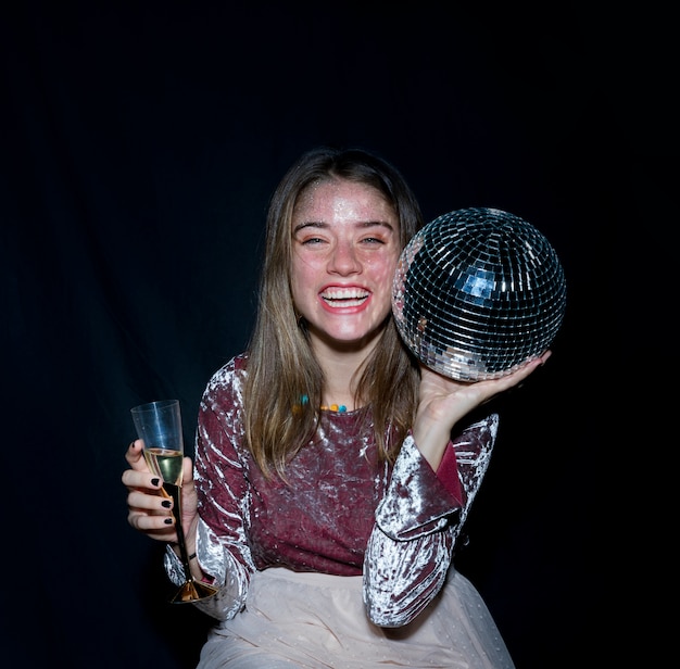 Mujer feliz sentada con bola de discoteca en la mano